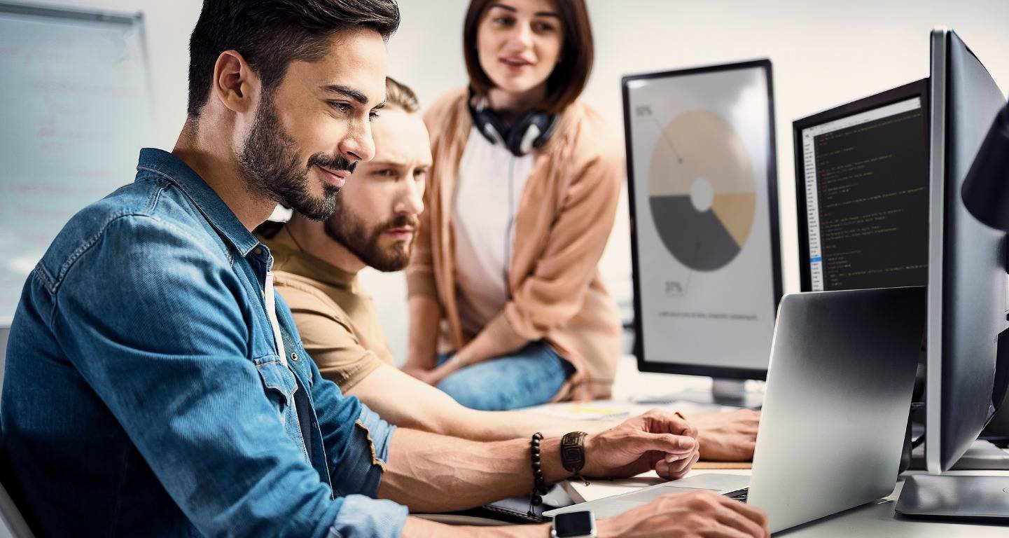 Colleagues working together at computer monitors showing charts