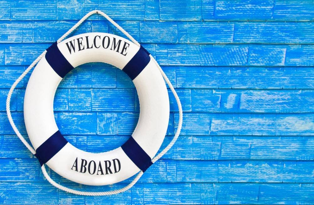Life ring reading Welcome Aboard on a blue wooden wall