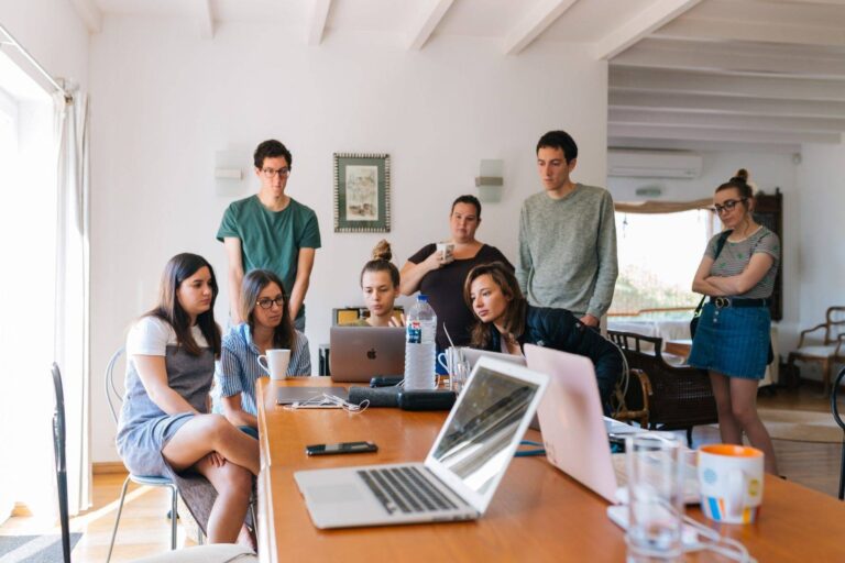 Team gathered around a table with laptops in a bright office