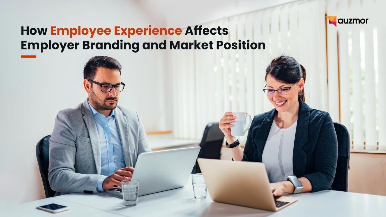 Two colleagues working on laptops across a desk, with the title How Employee Experience Affects Employer Branding and Market Position