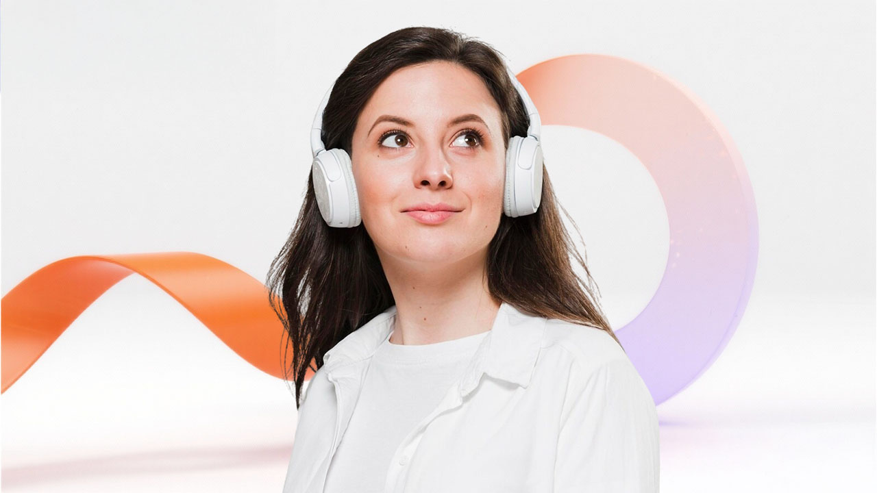 Woman wearing headphones looking up thoughtfully against a white background