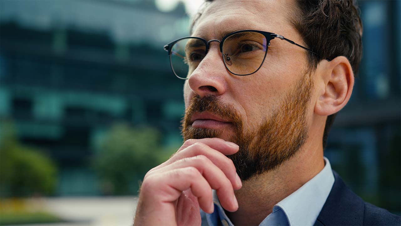 Thoughtful man in glasses with his hand on his chin