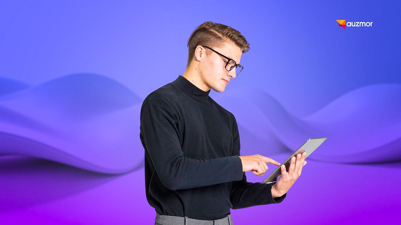 Young man in glasses tapping a tablet against a purple gradient background