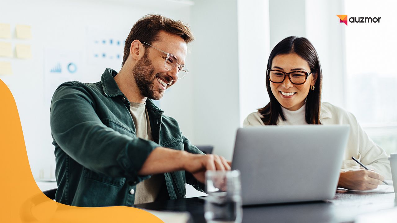 Two colleagues smiling while working together on a laptop