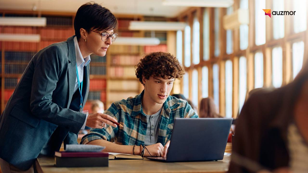 Instructor guiding a student working on a laptop in a library