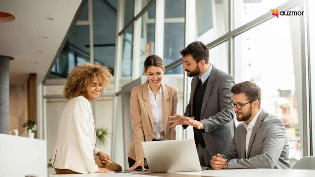 Team gathered around a laptop in a bright office discussing course administration