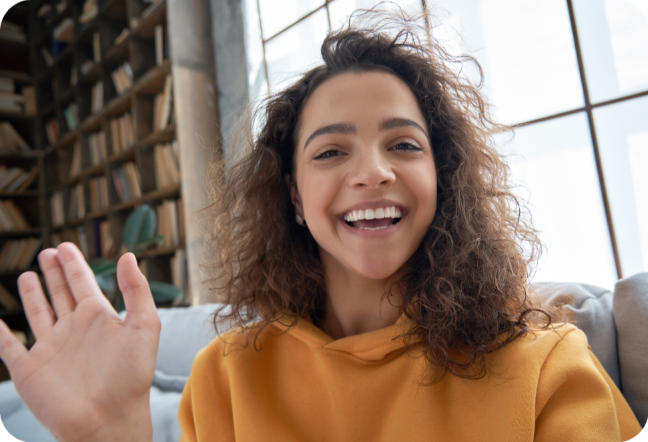 Woman waving on a video call while learning from home