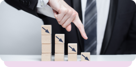 Hand pointing at descending wooden blocks, illustrating revenue lost to non-compliance