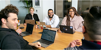 Team meeting around a conference table with laptops, representing a leadership development series