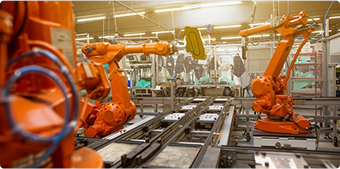 Robotic arms on a factory production line, representing a custom manufacturing safety program