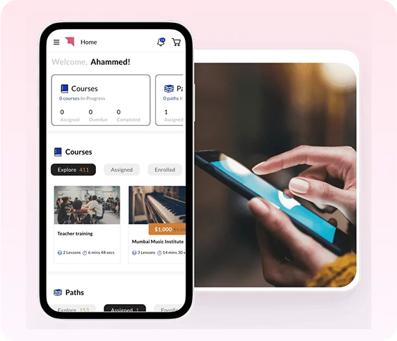 Auzmor Learn mobile app home screen showing courses and paths, next to a hand using a phone