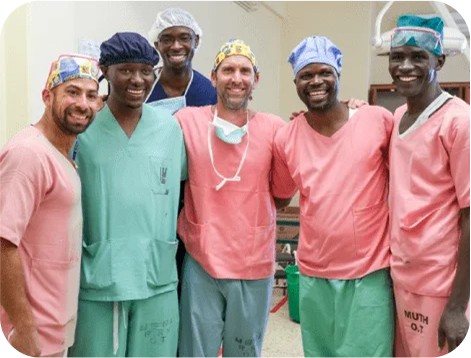 Medical team in scrubs and surgical caps smiling together in a hospital