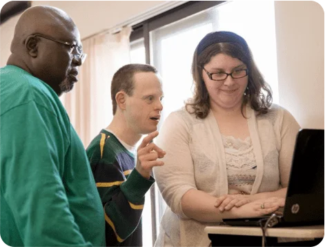 Homeward Bound staff member helping two colleagues at a computer workstation