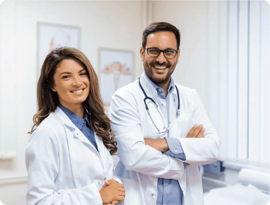 Two smiling doctors in white coats standing in a clinic