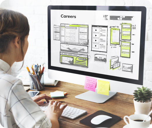 Designer laying out a careers page wireframe on a desktop monitor