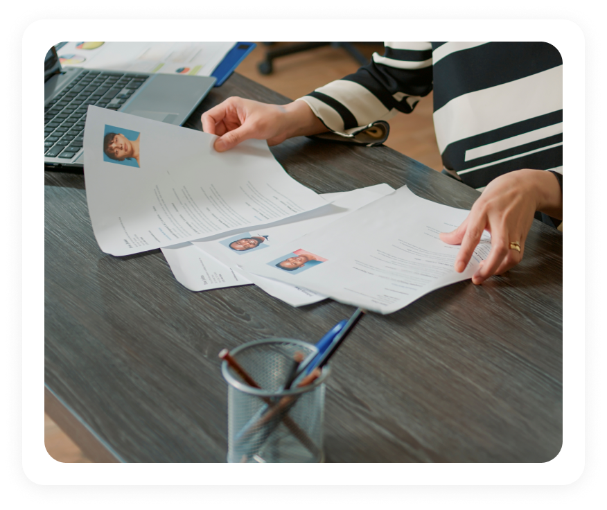 Recruiters spreading printed resumes across a table to source talent