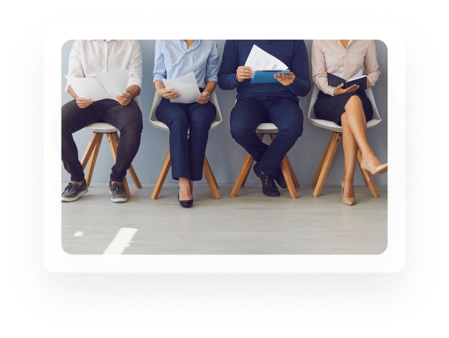 Candidates seated in a row holding resumes while waiting to interview