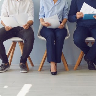 Candidates seated in a row holding resumes while waiting to interview
