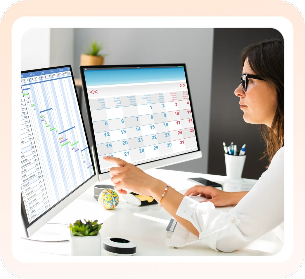 Woman managing calendars on two desktop monitors