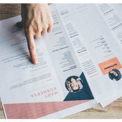 Finger pointing at details on printed candidate resumes