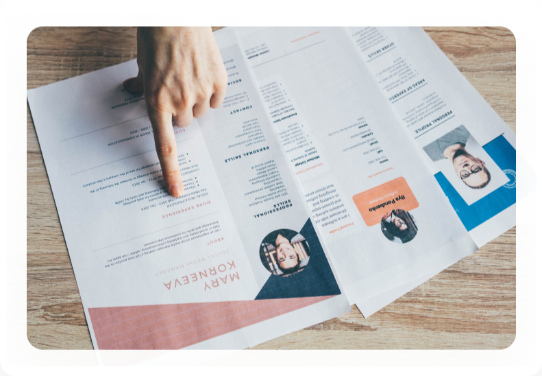 Finger pointing at details on printed candidate resumes
