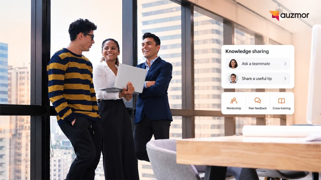 Three colleagues laughing around a laptop by an office window, next to an Auzmor knowledge-sharing card with Ask a teammate, Share a useful tip, Mentorship, Peer feedback and Cross-training