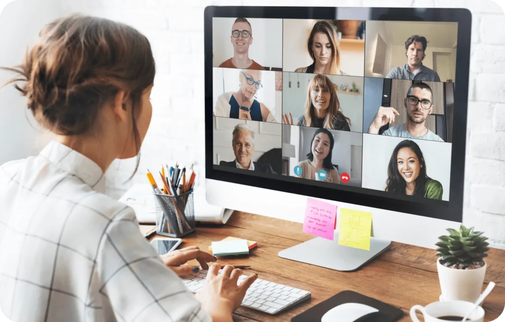 Employee on a video call with colleagues shown in a grid on a desktop monitor