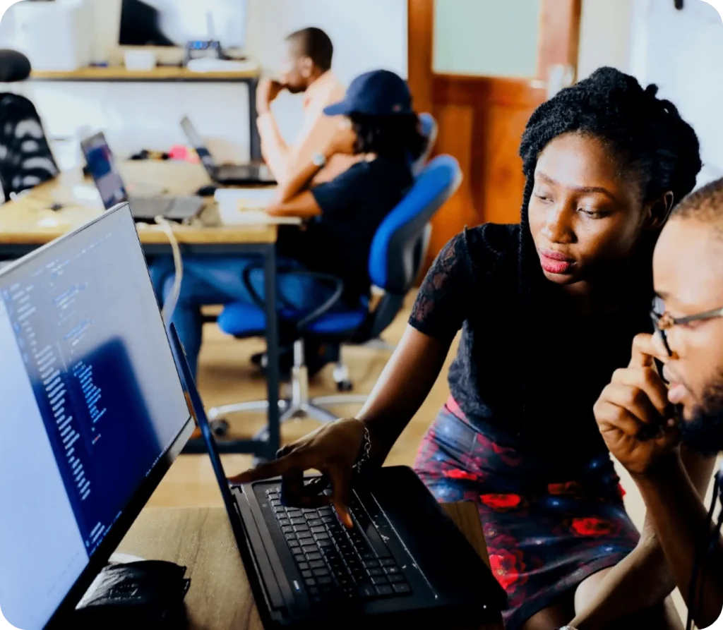 Employees collaborating on laptops in a busy open-plan office