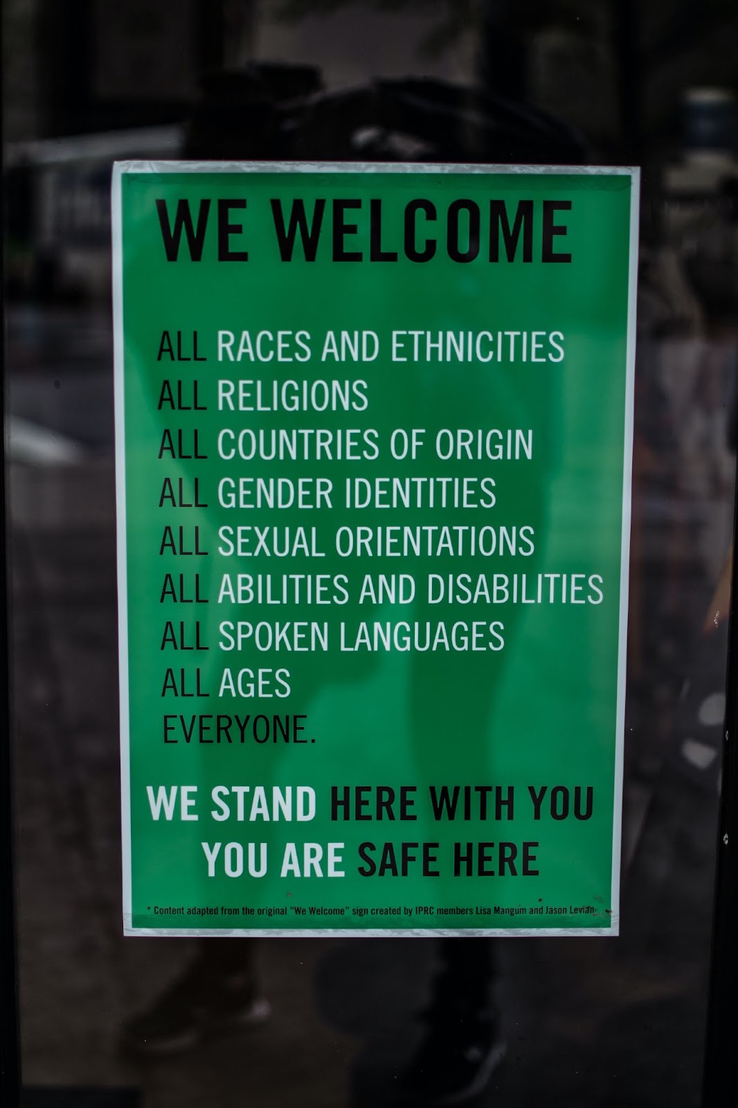 Green sign reading "We welcome all races, religions, countries of origin, gender identities, sexual orientations, abilities, languages and ages"